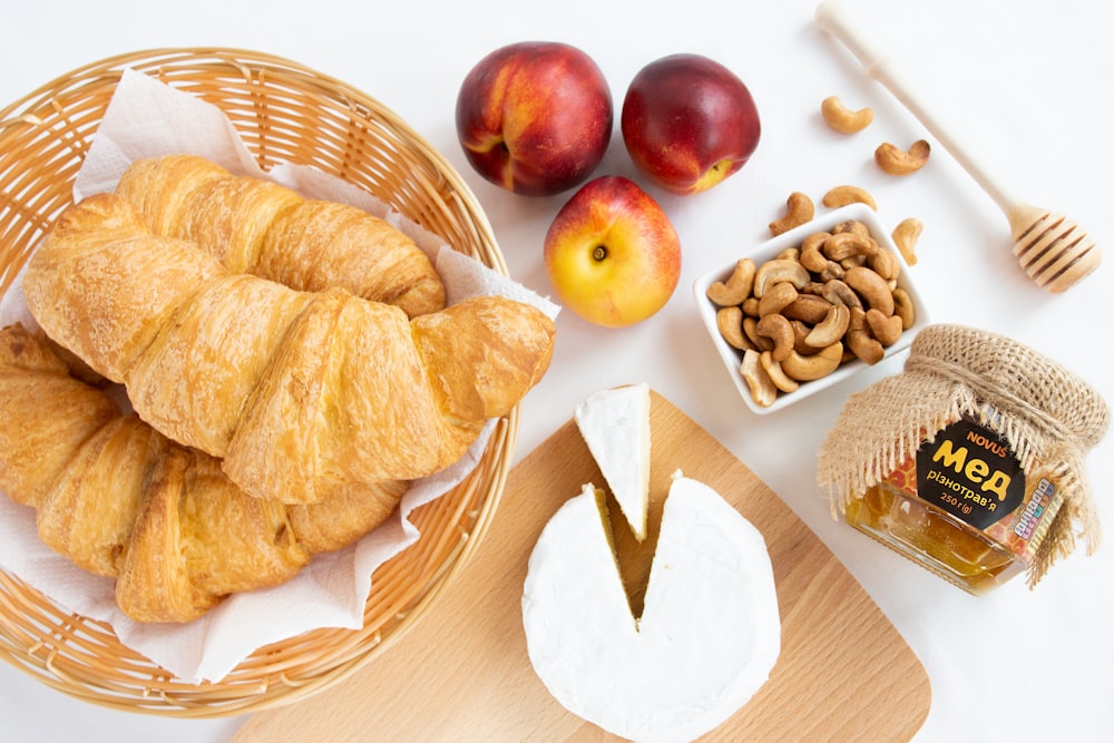 a basket of croissants, apples, nuts, and honey on a