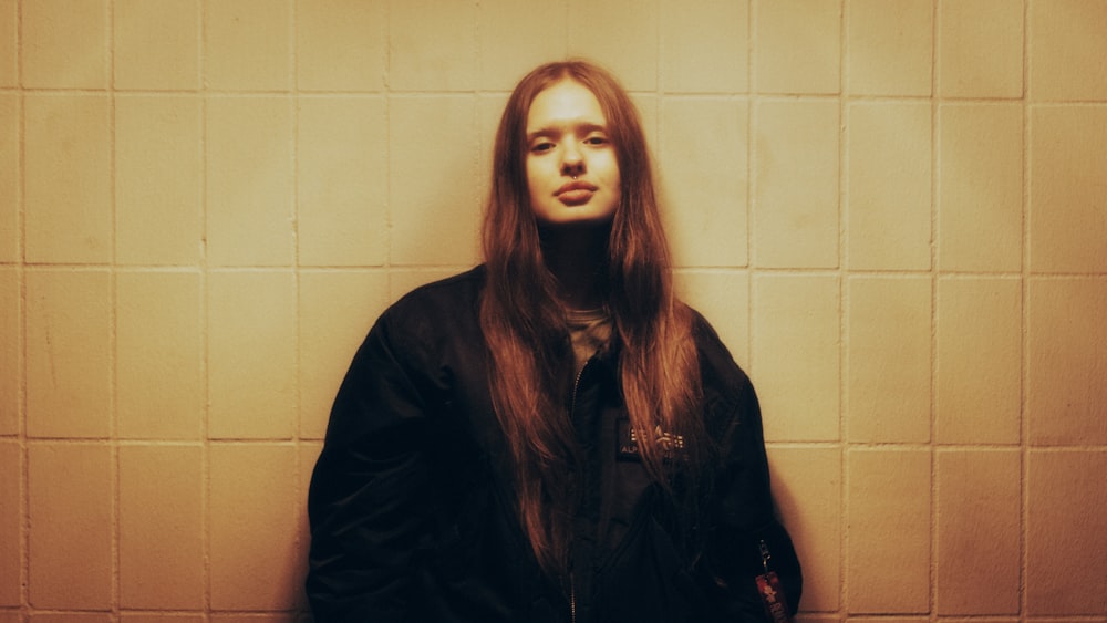 a woman with long hair standing in front of a wall