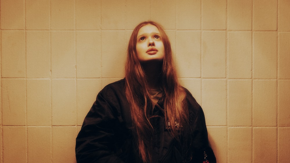 a woman with long hair standing in front of a wall