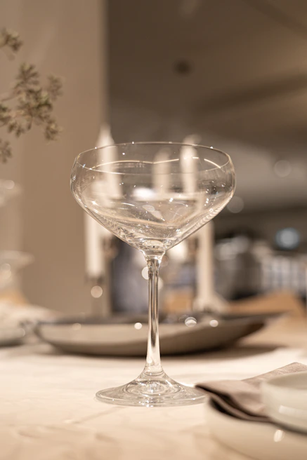 An elegant cocktail setup with delicate glassware and soft ambient lighting in a Provençal garden.