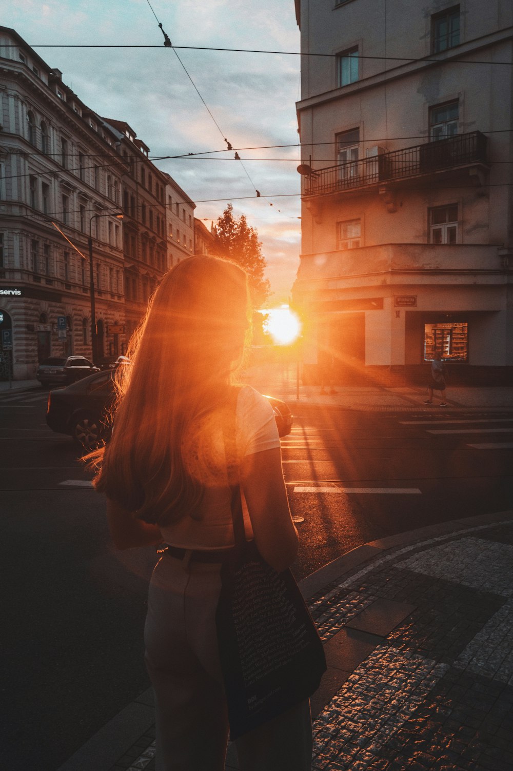 a woman standing in the middle of a street at sunset