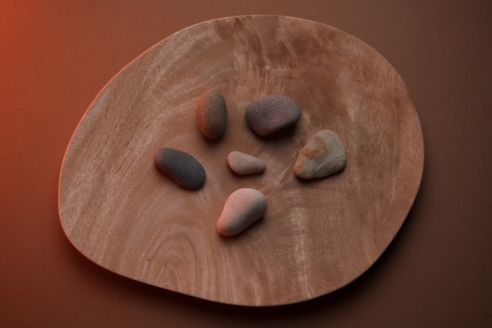 a wooden plate topped with rocks on top of a table