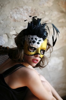 a woman wearing a mask with feathers on her head