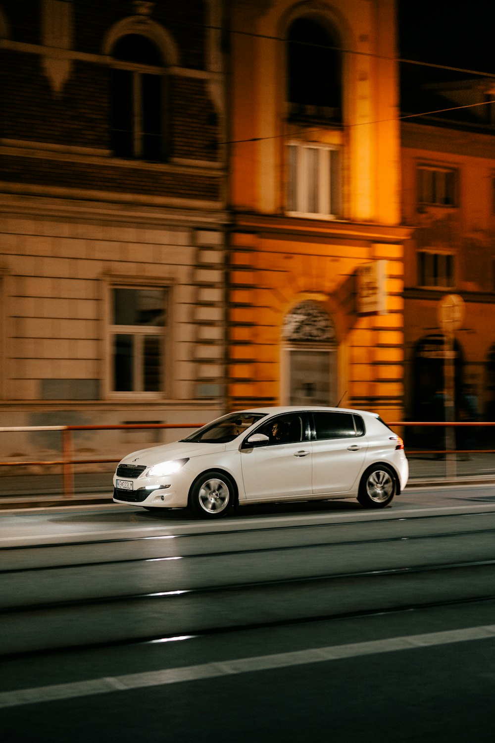 a white car driving down a street next to a tall building