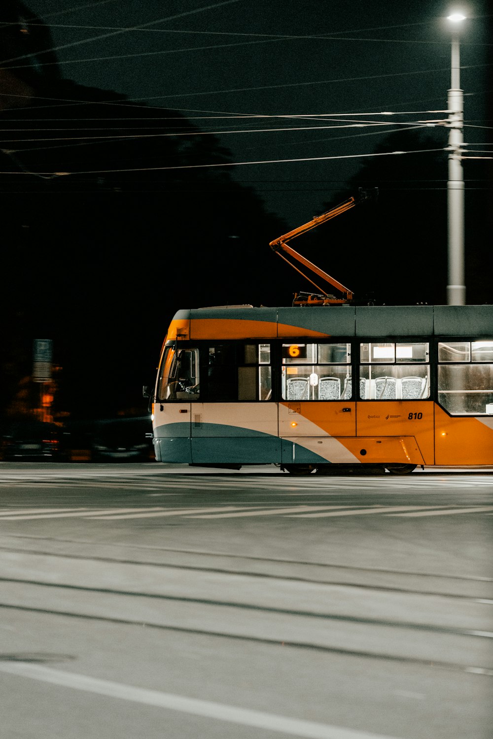 an orange and blue trolley on a city street at night