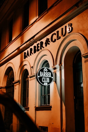Barbershop entrance lit warmly at night with the Tiburcio's logo visible.