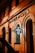 A warmly lit facade of a building featuring an illuminated sign with the text 'Barber Club' in a stylish font. The architecture includes arched windows and a classic design, contributing to a vintage and inviting atmosphere.