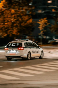 A mobile patrol vehicle driving through an industrial estate at night.