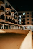 Evening view of a residential complex with warm lights and green balconies.