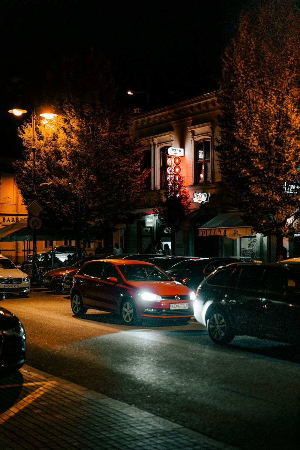 uma rua da cidade à noite com carros estacionados à beira da estrada