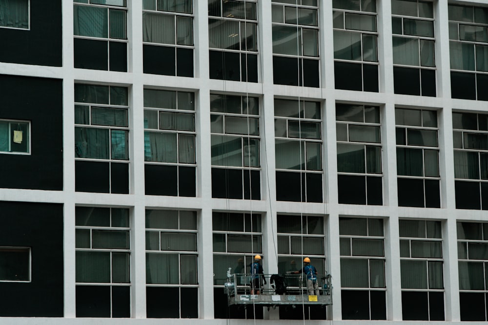 a couple of men standing on a scaffold in front of a tall building