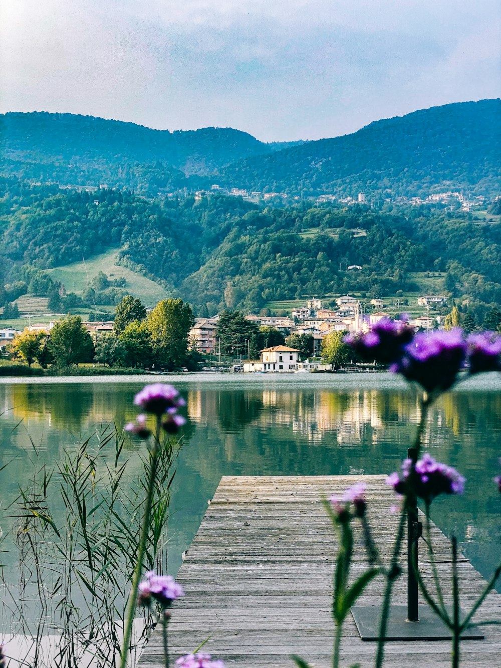 a wooden dock sitting on top of a lake next to a lush green hillside