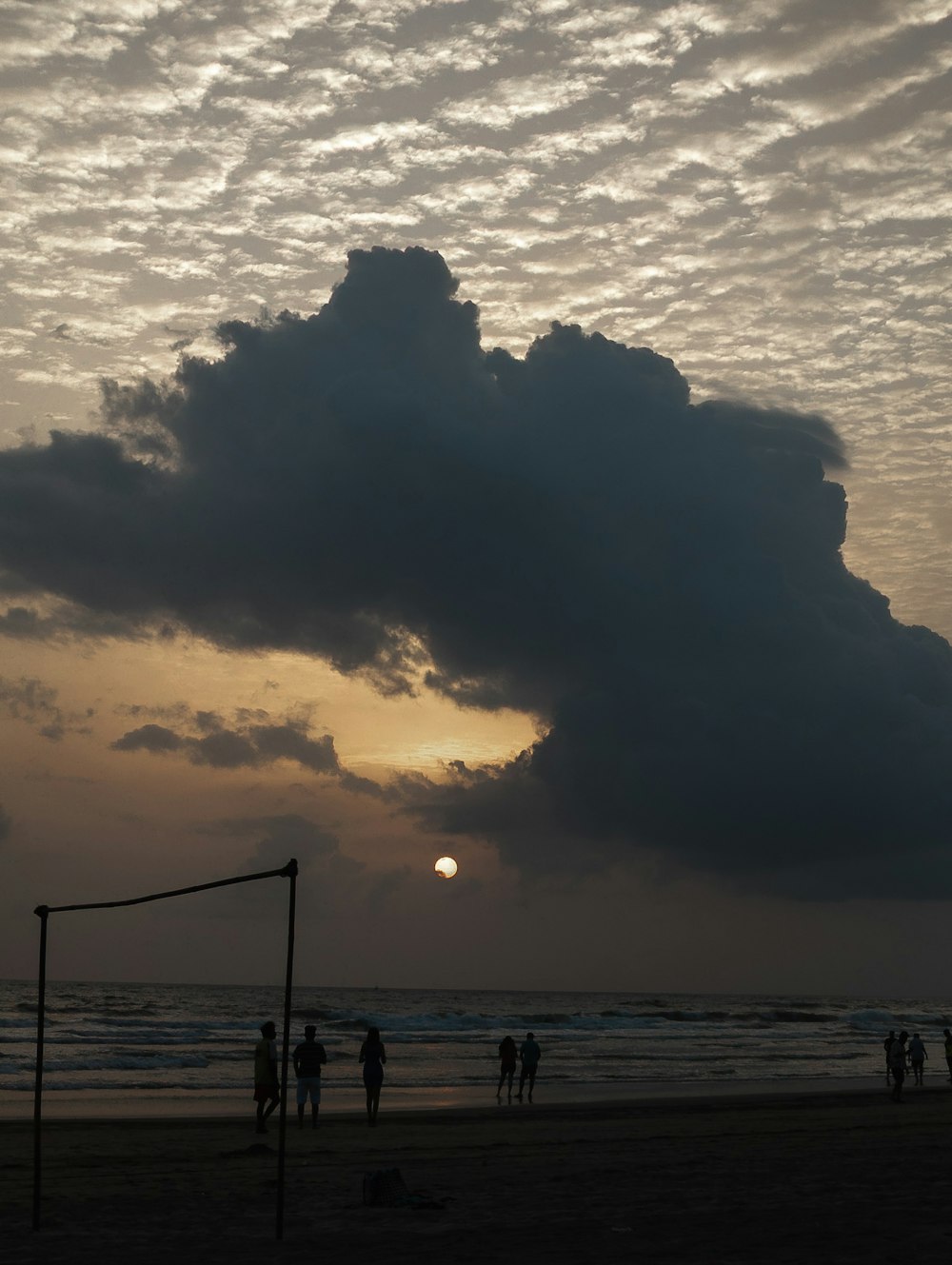 a group of people standing on top of a beach under a cloudy sky