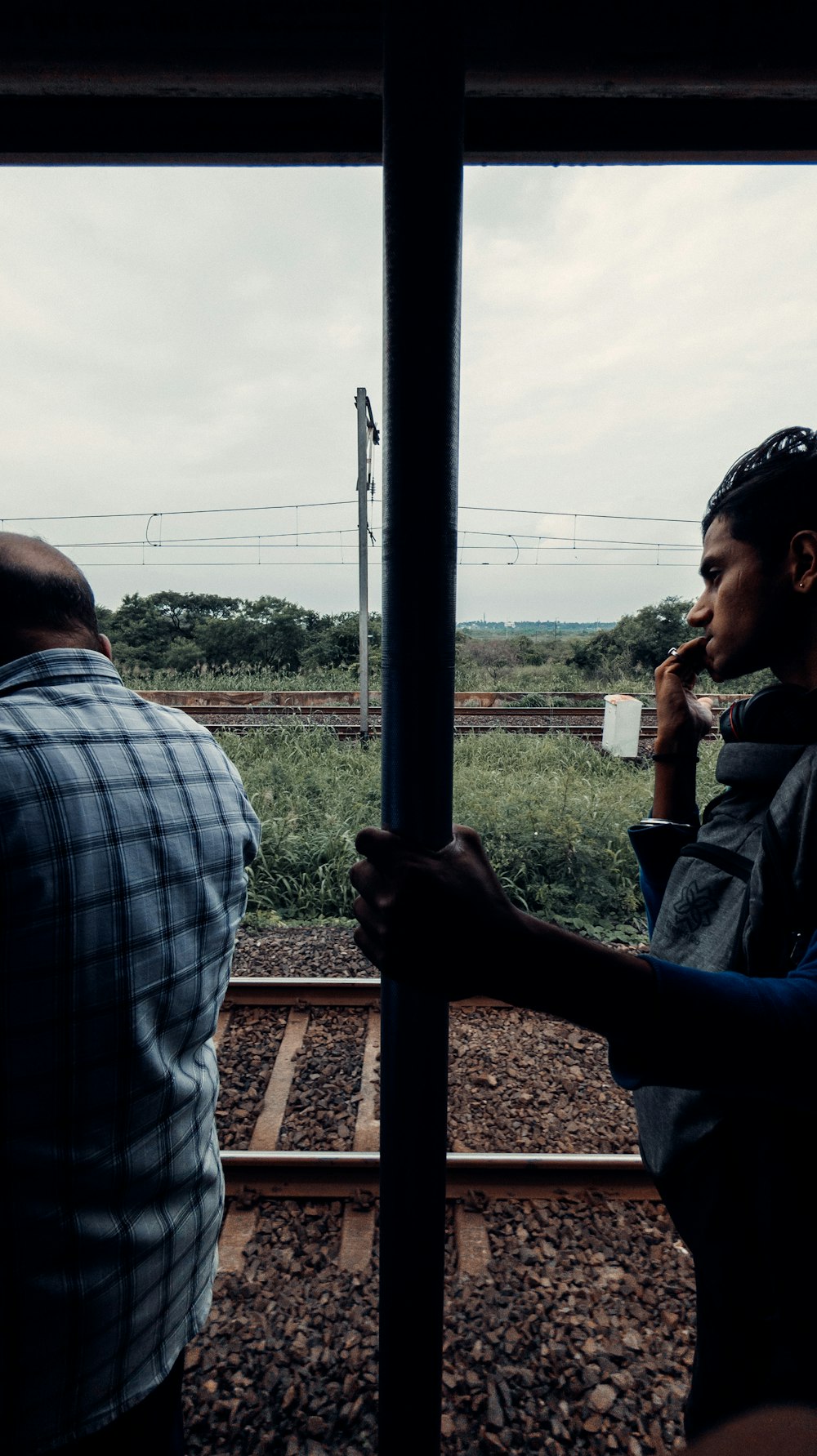 a couple of men standing next to each other on a train