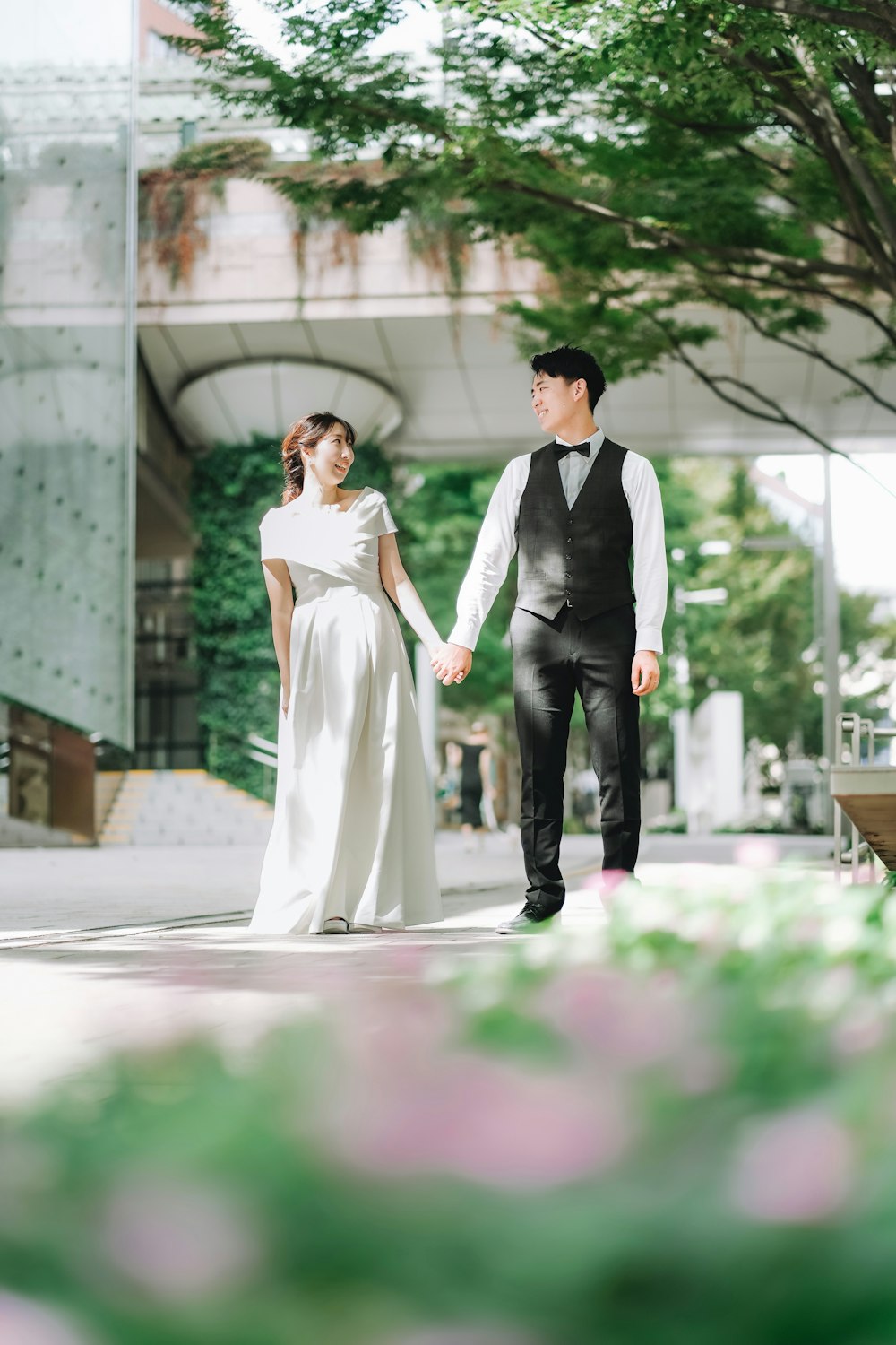 a man and a woman holding hands in front of a building