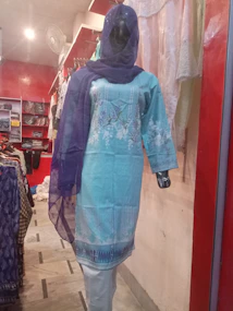 Silk salwar suit draped elegantly on a mannequin, glowing softly under warm lighting.