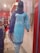 A mannequin is dressed in a light blue embroidered kurta with white floral patterns, paired with a matching blue dupatta. The mannequin is displayed in a clothing store with a red and white interior. Various fabrics and garments are visible in the background.