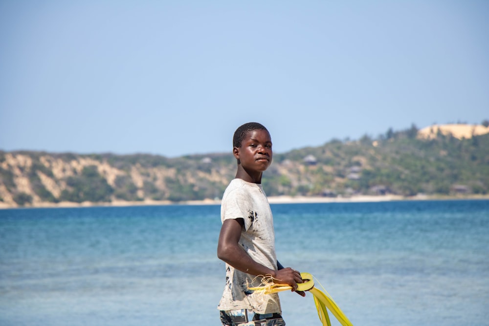 a young boy holding a yellow frisbee on a beach