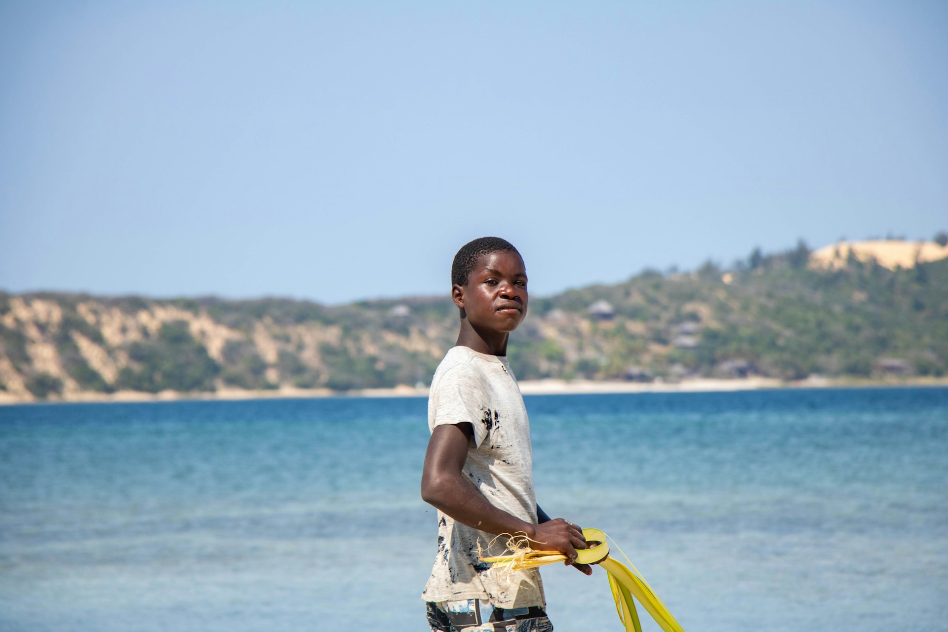 Jeune garçon jouant avec un frisbee jaune sur la plage profitant des activités balnéaires