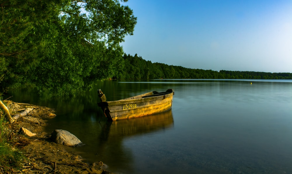 a boat sitting on top of a lake next to a forest