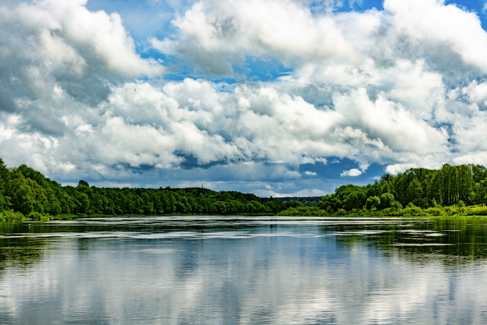 a body of water surrounded by trees and clouds