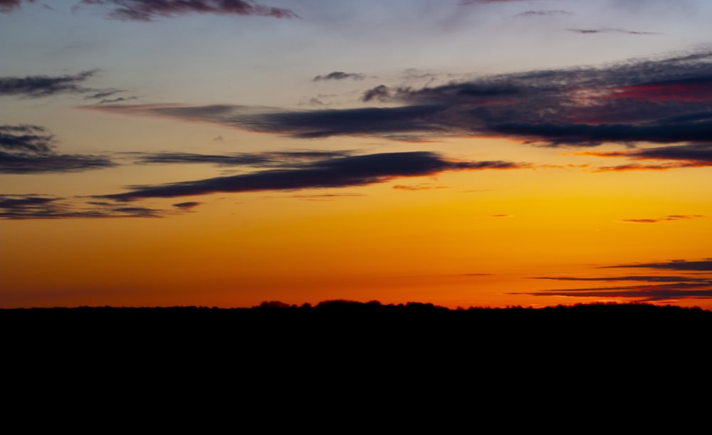 a plane flying in the sky at sunset