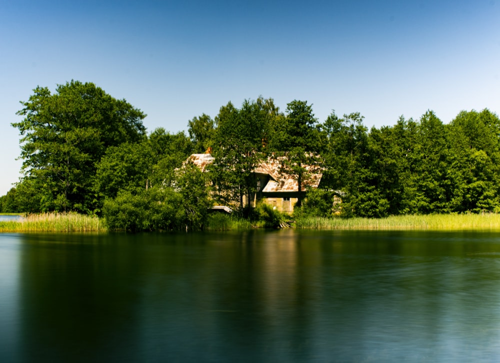 a house on the shore of a lake surrounded by trees