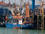 Wide angle view of a colorful fishing boat hull docked at a bustling harbor.