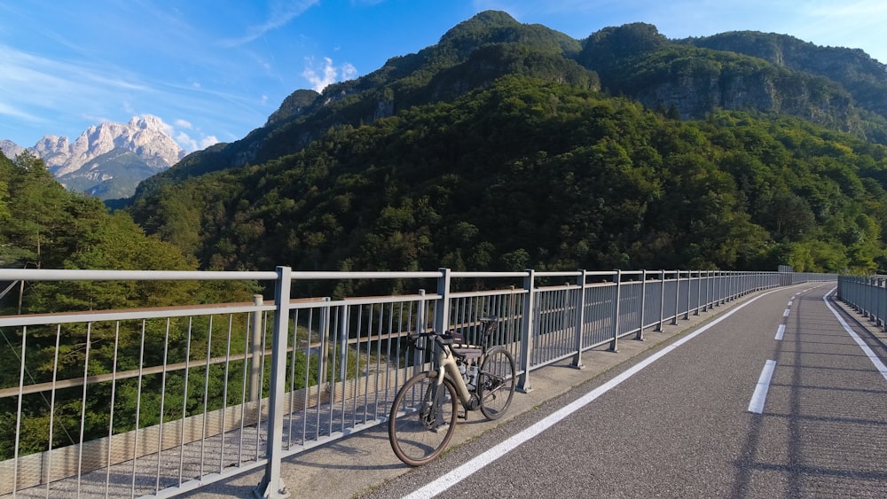 a bicycle parked on the side of a road next to a fence