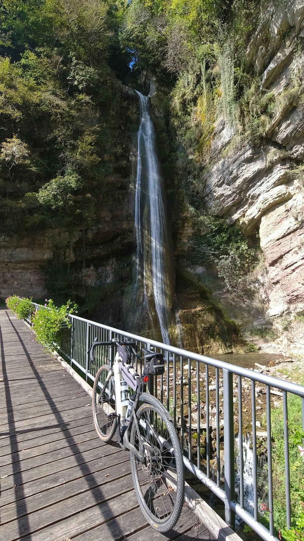 a bicycle parked on a bridge next to a waterfall