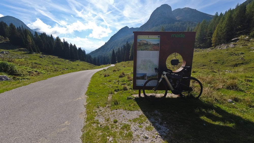 a bike parked next to a sign on the side of a road