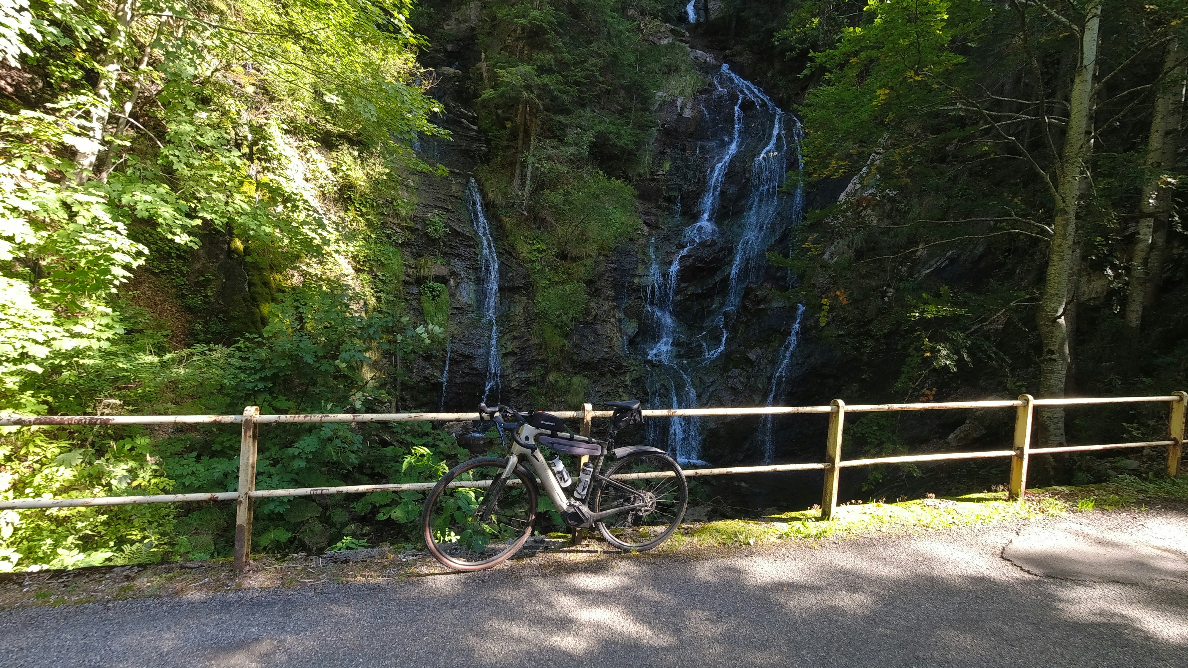 a bike parked next to a wooden fence near a waterfall