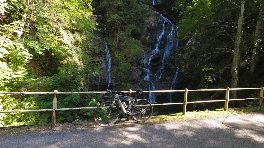 a bike parked next to a wooden fence near a waterfall