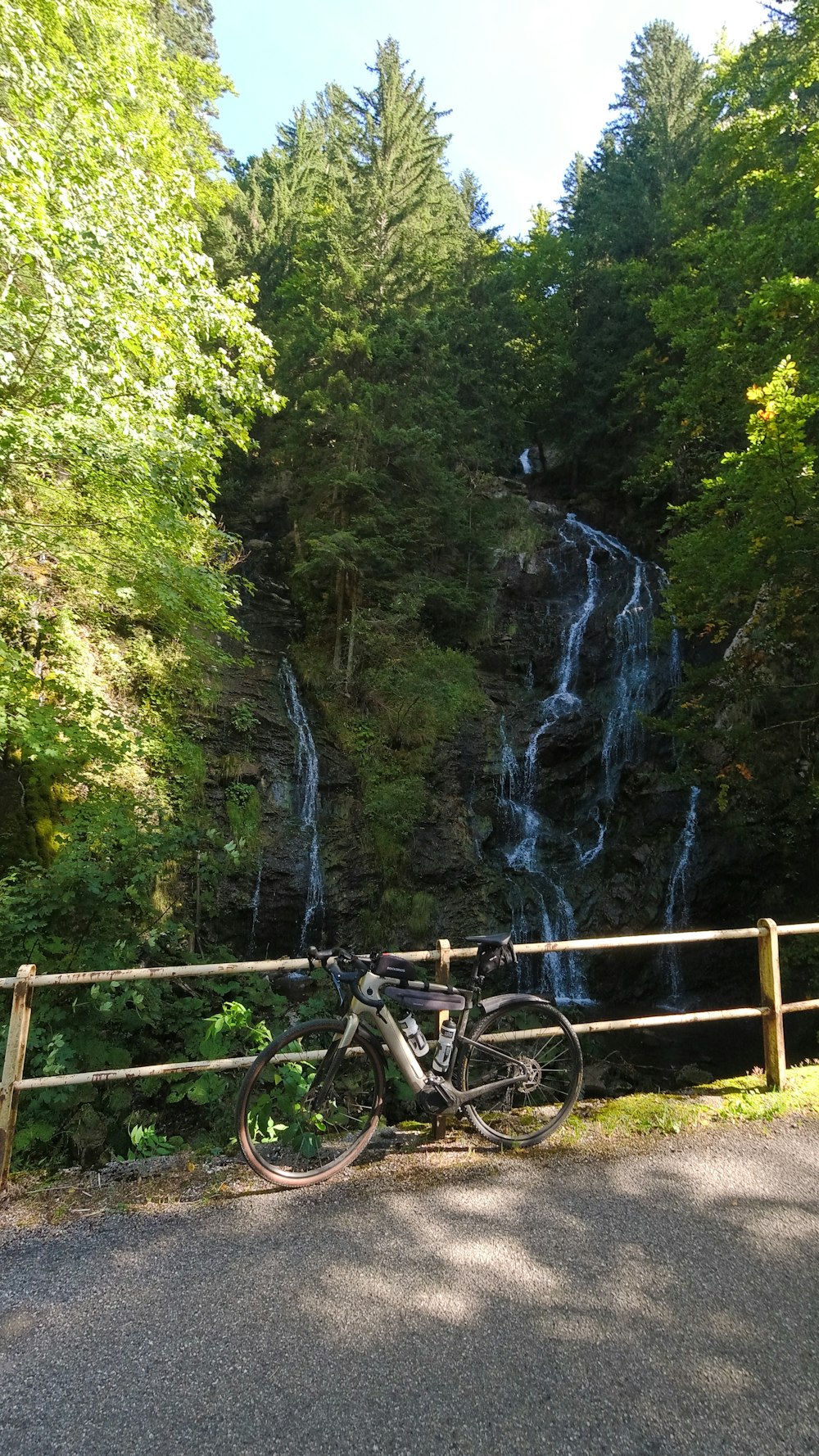 a bike parked next to a wooden fence near a waterfall