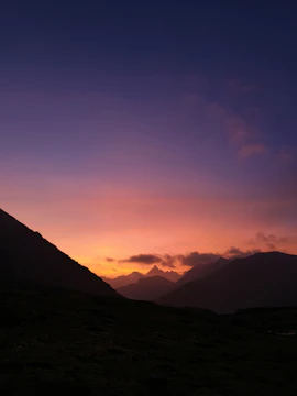 A wide-angle shot of a serene mountain landscape at sunset with vibrant colors.