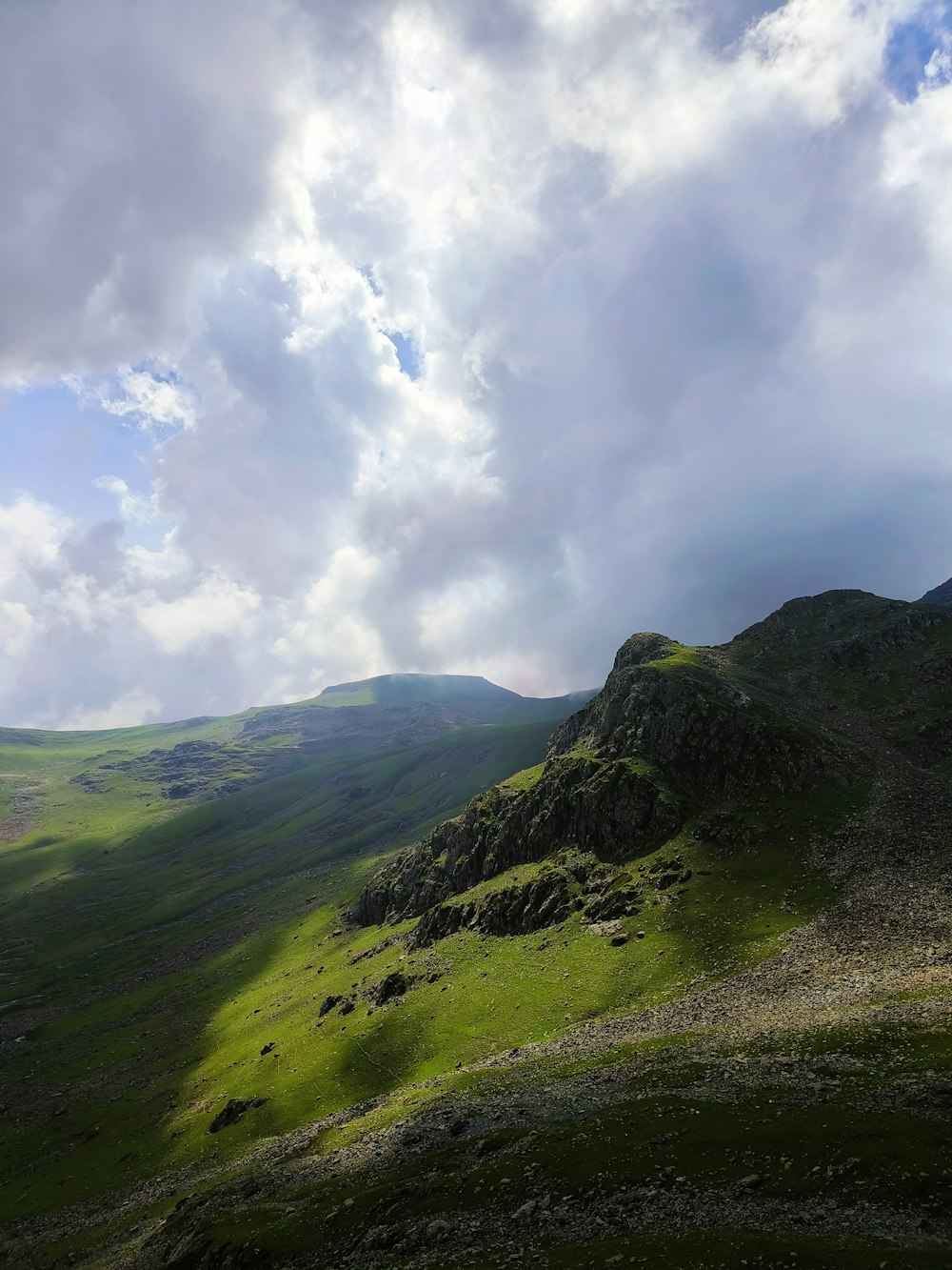 a grassy hill with a cloudy sky in the background