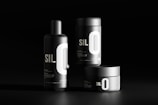 Three black cylindrical containers are displayed against a dark background. Each features bold white typography with the letters 'SIL O' prominently visible. The sleek, minimalist design emphasizes a modern aesthetic.