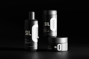 Three black cylindrical containers are displayed against a dark background. Each features bold white typography with the letters 'SIL O' prominently visible. The sleek, minimalist design emphasizes a modern aesthetic.