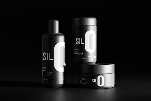 Three black cylindrical containers are displayed against a dark background. Each features bold white typography with the letters 'SIL O' prominently visible. The sleek, minimalist design emphasizes a modern aesthetic.