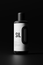A cylindrical black and white bottle with the text 'SILO' prominently displayed on its label. The background is dark, creating a stark contrast with the bright label, highlighting the bottle.