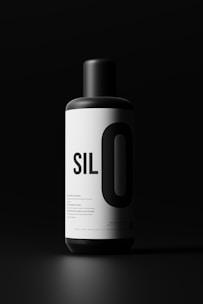 A cylindrical black and white bottle with the text 'SILO' prominently displayed on its label. The background is dark, creating a stark contrast with the bright label, highlighting the bottle.