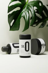 Aluminium containers with eco-friendly labels surrounded by fresh green leaves.