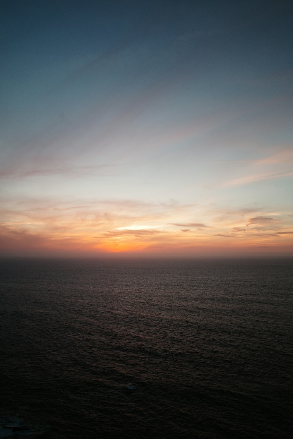 the sun is setting over the ocean on a cloudy day