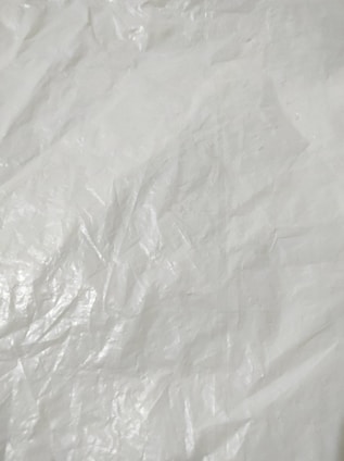 Crumpled and textured white surface with subtle shadows and highlights, resembling plastic or fabric material.