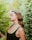 a woman standing in front of a bush with her eyes closed
