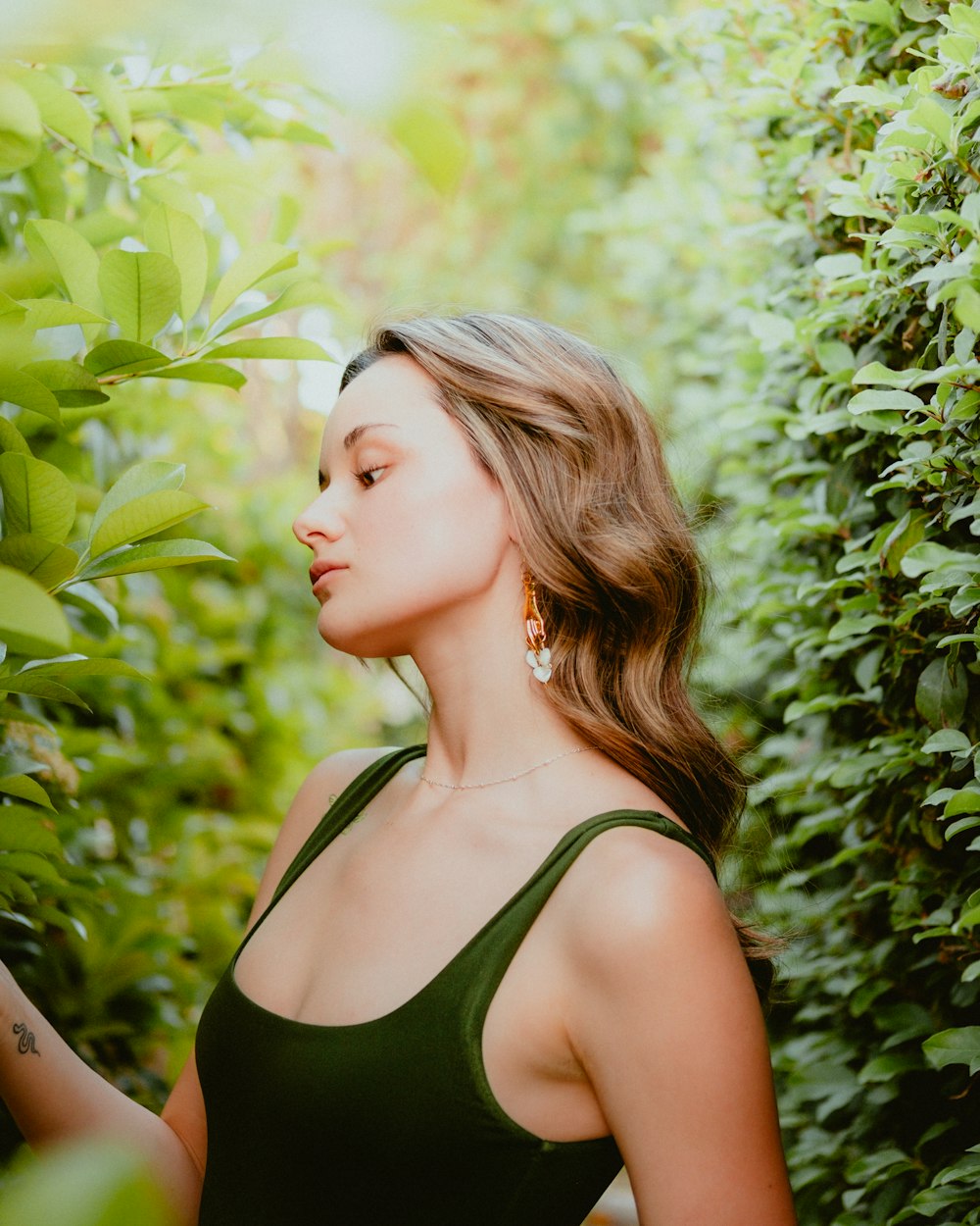 una mujer de pie frente a un arbusto con los ojos cerrados