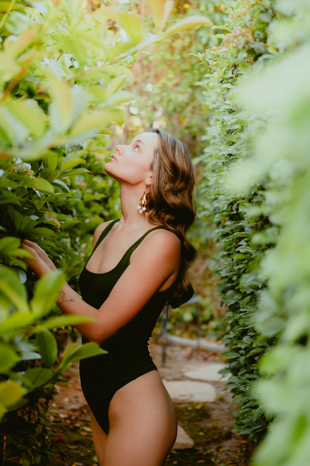 a woman in a black swimsuit standing in a garden