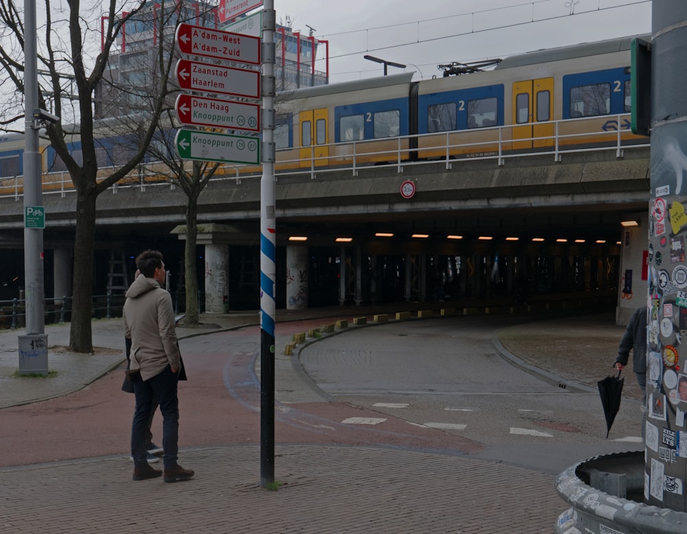 a man standing on a street corner next to a train