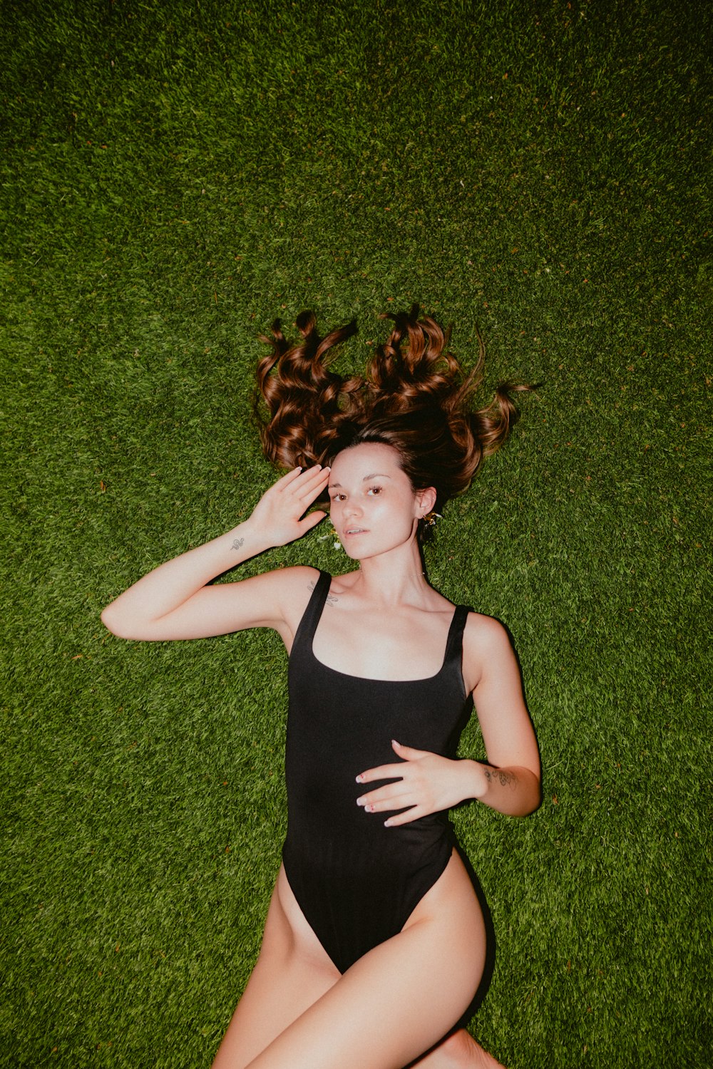 a woman laying on the grass with her hair in the air