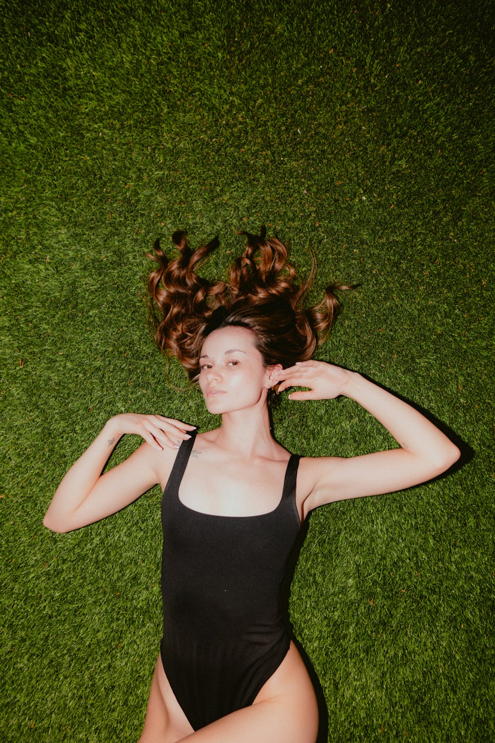 a woman laying on the grass with her hair in the air